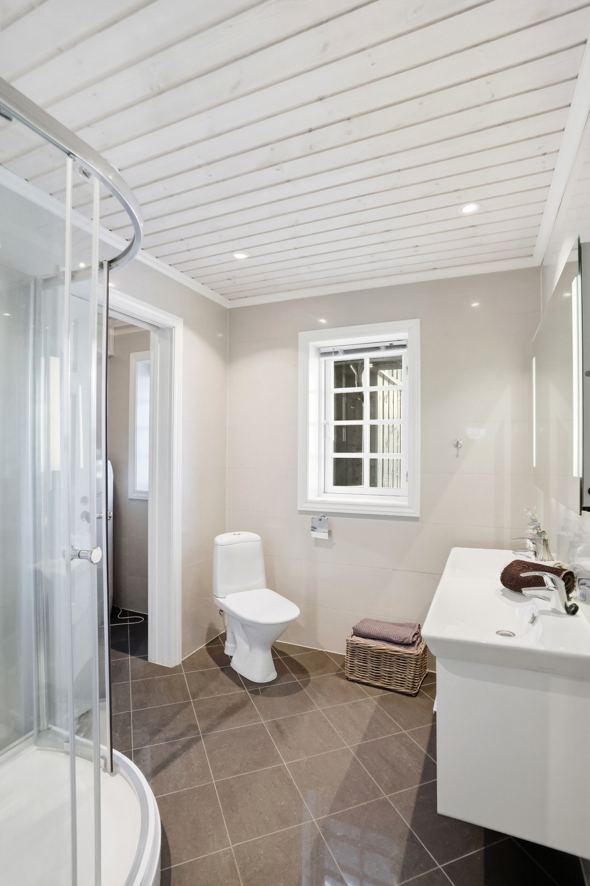 Flislagt baderom med toalett, innredning med servant og dusjkabinett. Fra badet er tilkomst til teknisk rom med opplegg til vaskemaskin Galleribilde