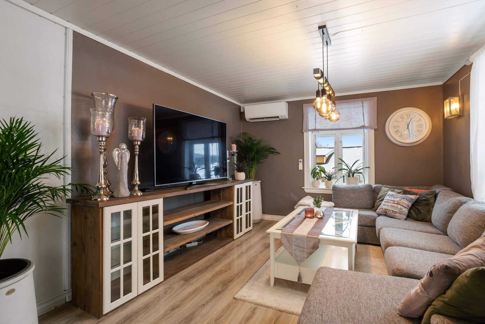 Pen stue/TV-stue med malte veggflater, panelt himling og varmepumpe. Galleribilde