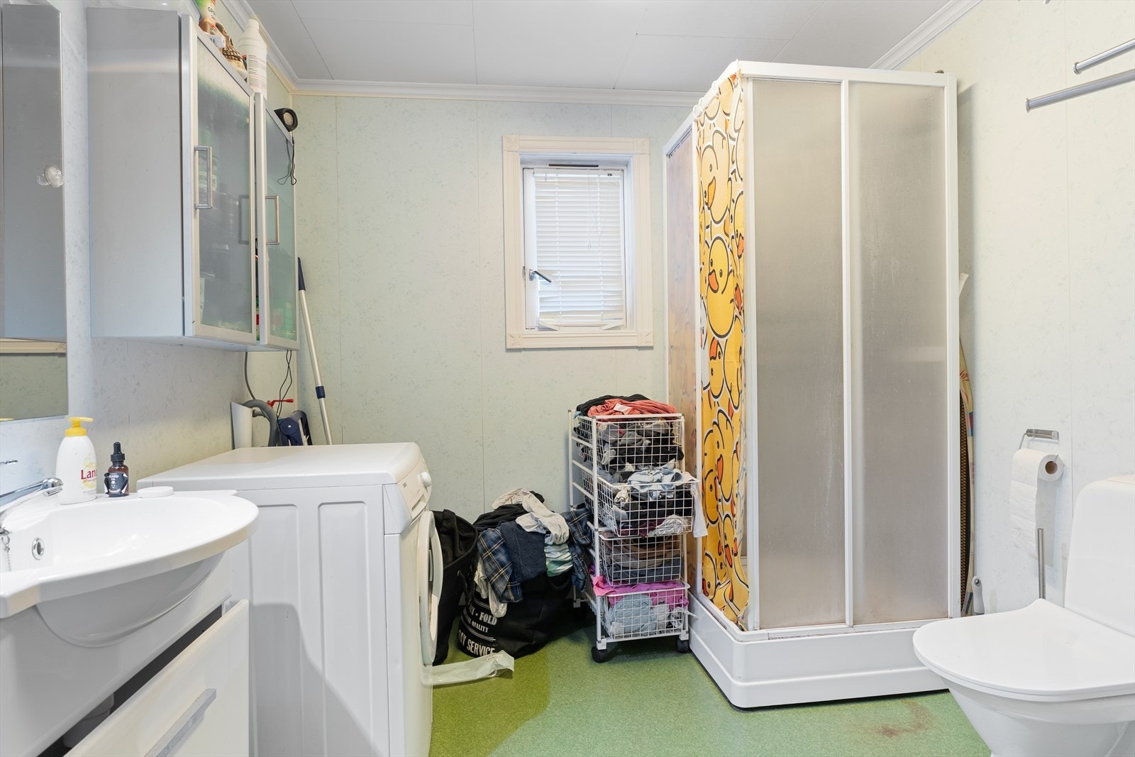 Romslig bad som inneholder toalett, dusjkabinett, innredning med servant og opplegg for vaskemaskin Galleribilde