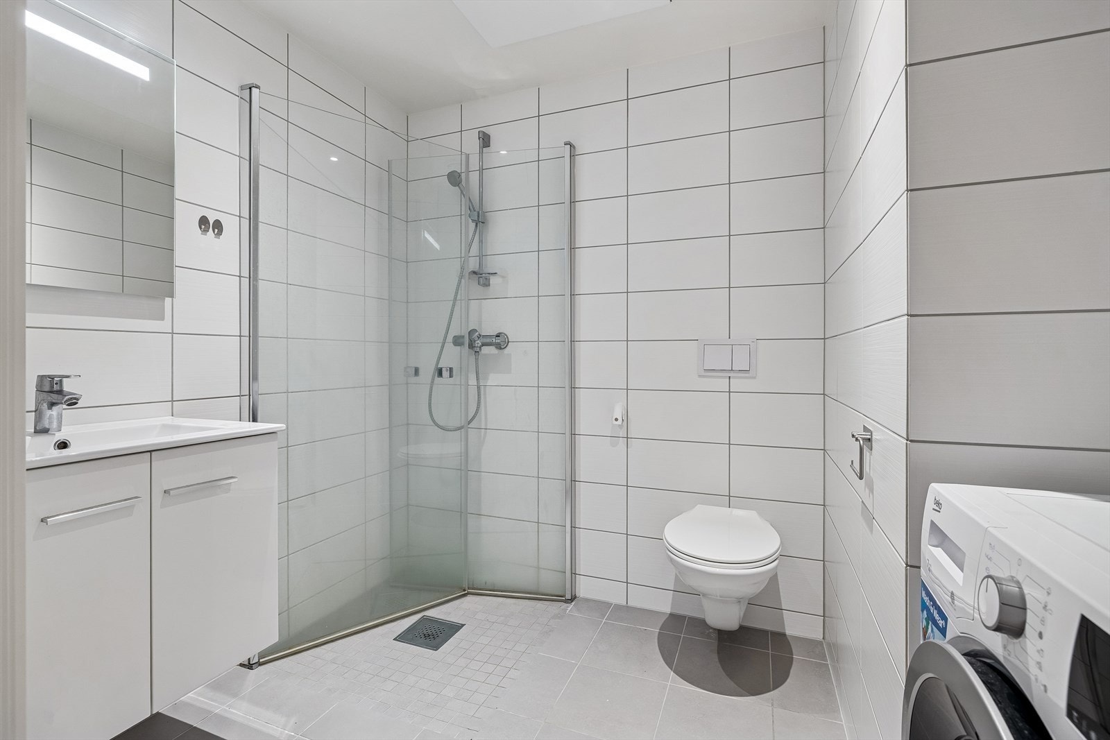 Flislagt baderom med opplegg for vaskemaskin. Galleribilde