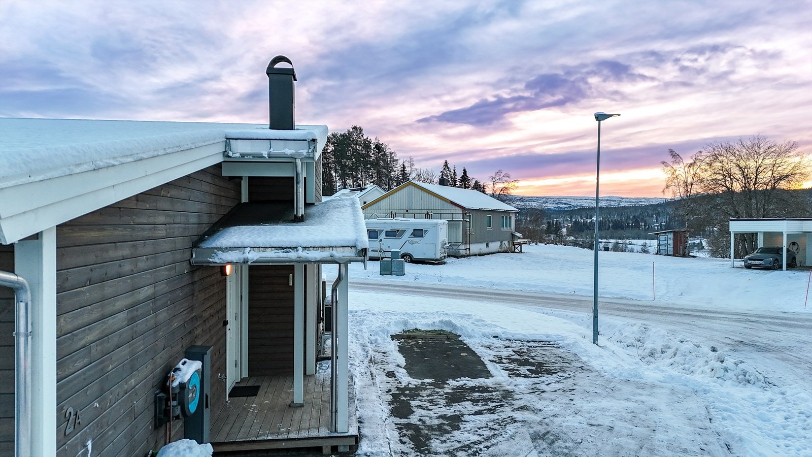 Asfaltert adkomst, samt frodig plen som omgir boligen sommerstid. Galleribilde