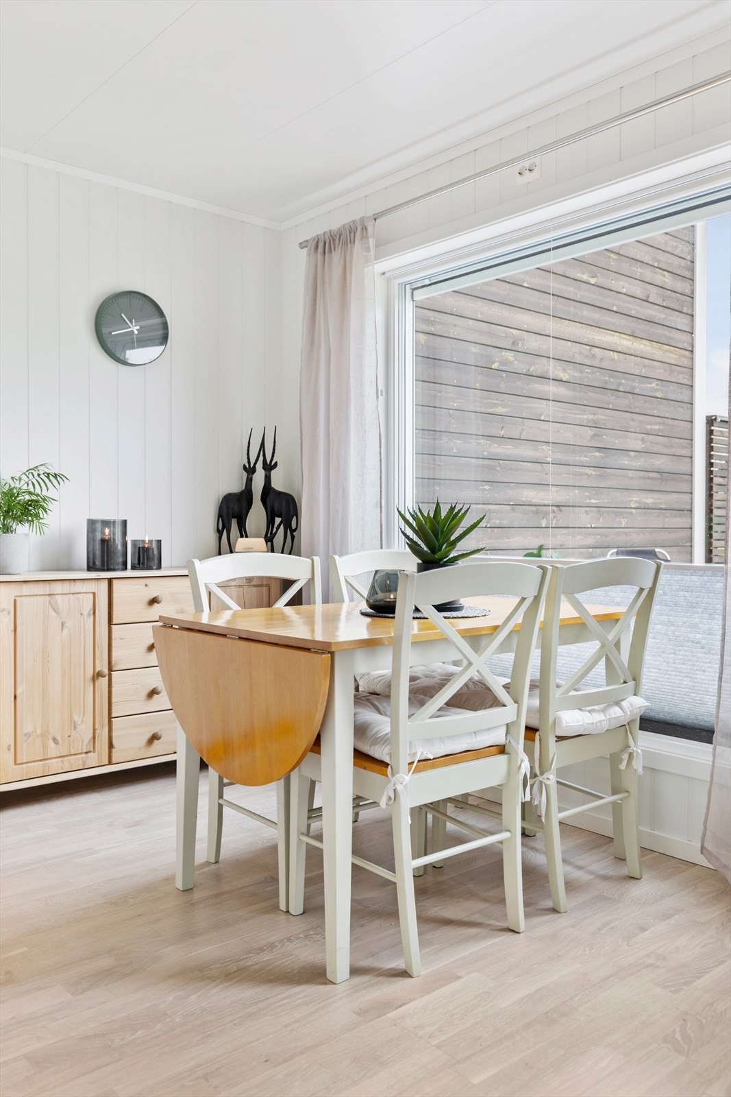 Spiseplass rett ved de store vinduene som har utsikt til boligens terrasse og hage. Galleribilde