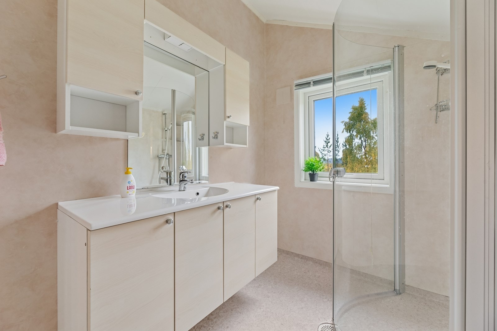 Badet har vegger med våtromstapet og malt himling, samt gulv med slitesterkt vinylbelegg. Rommet er utstyrt med veggmontert toalett, nedfelt servant i innredning og dusjhjørne med dusjvegger, som gir en praktisk og plassbesparende løsning. Galleribilde