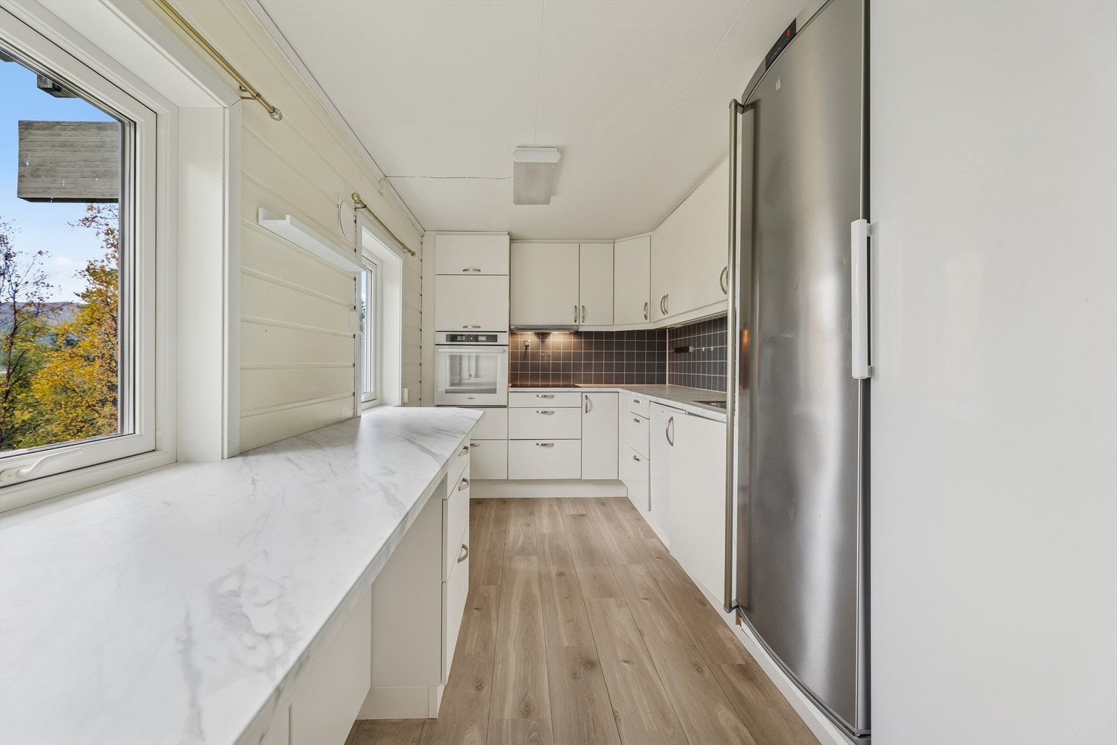 Kjøkkenet har innredning med glatte, hvite fronter og takhøye overskap som gir godt med oppbevaringsplass. Deler av kjøkkenet er fra 2015. Galleribilde