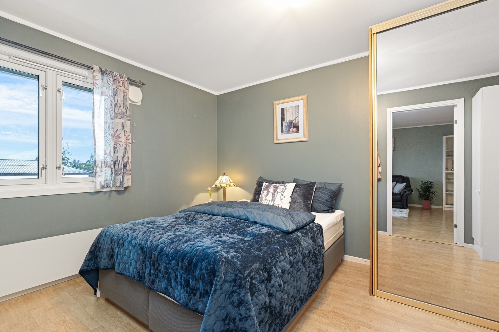 Gulv i laminat gir et slitesterkt underlag i soverommet, mens store vinduer slipper inn rikelig med dagslys. Galleribilde