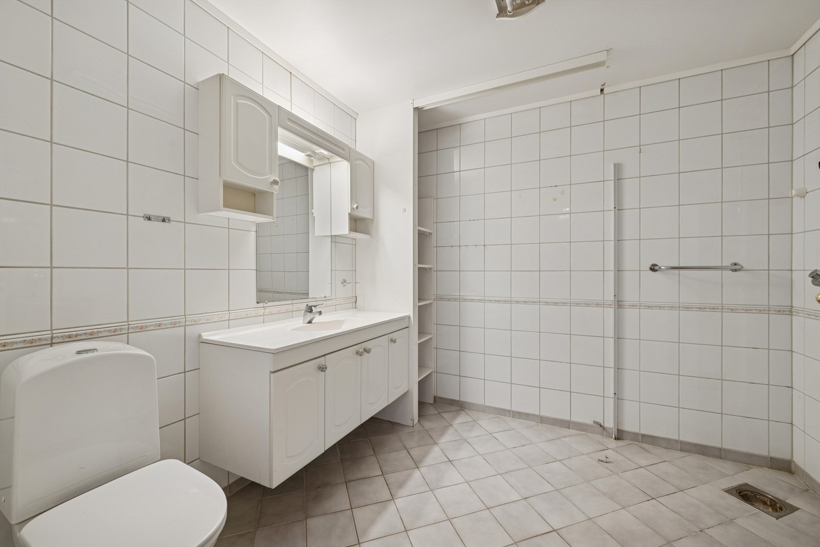 Badet er fra byggeår, fliser på gulv med undervarme, flislagte vegger og malt himling. Galleribilde