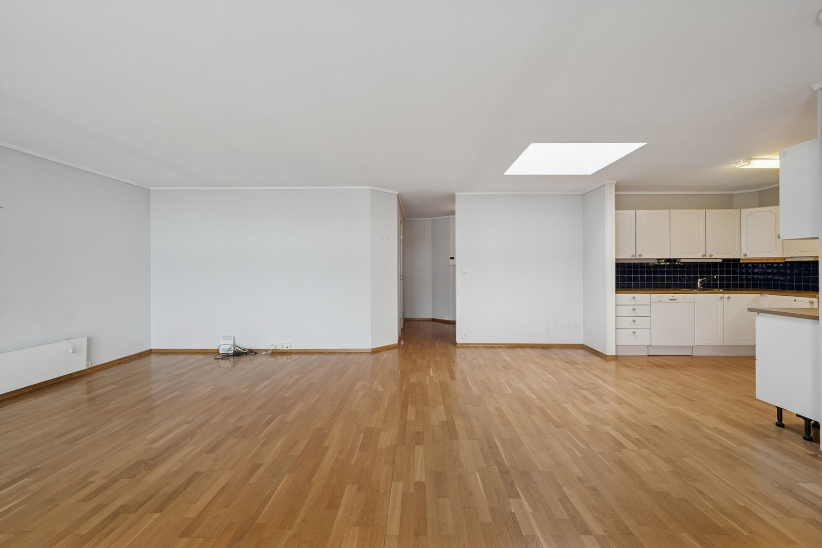 Lyst oppholdsrom med gjennomgående parkettgulv og lyse, nøytrale vegger. Galleribilde