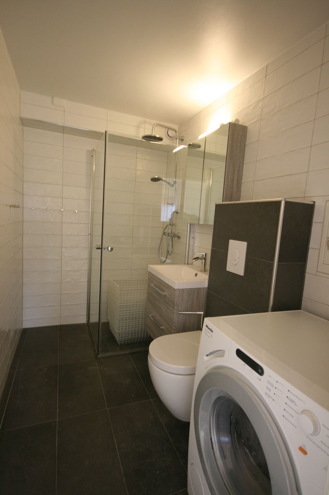 Nyere flislagt baderom med vaskemaskin. Galleribilde