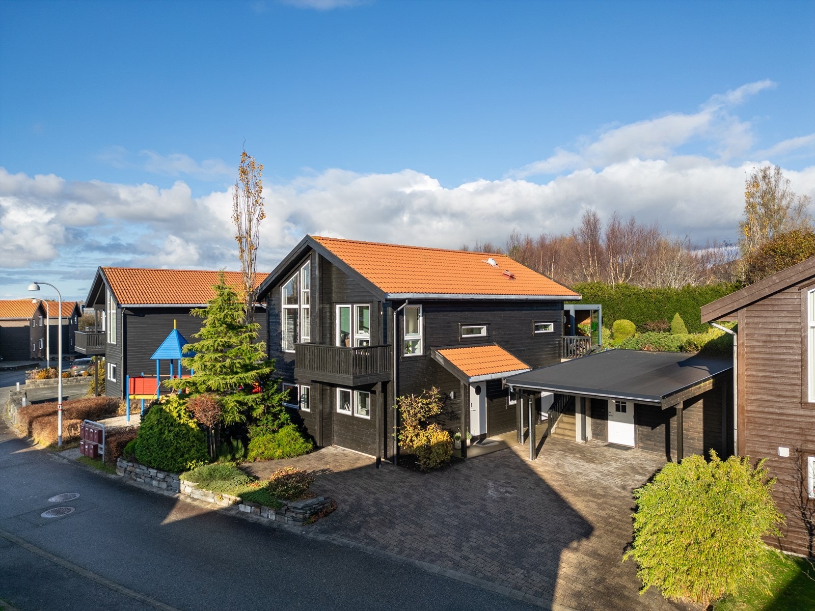 Eiendommen ligger i grønne og rolige omgivelser, med pent opparbeidet tomt, steinbelagt gårdsrom og carport som gir praktisk parkering og et ryddig helhetsinntrykk. Galleribilde