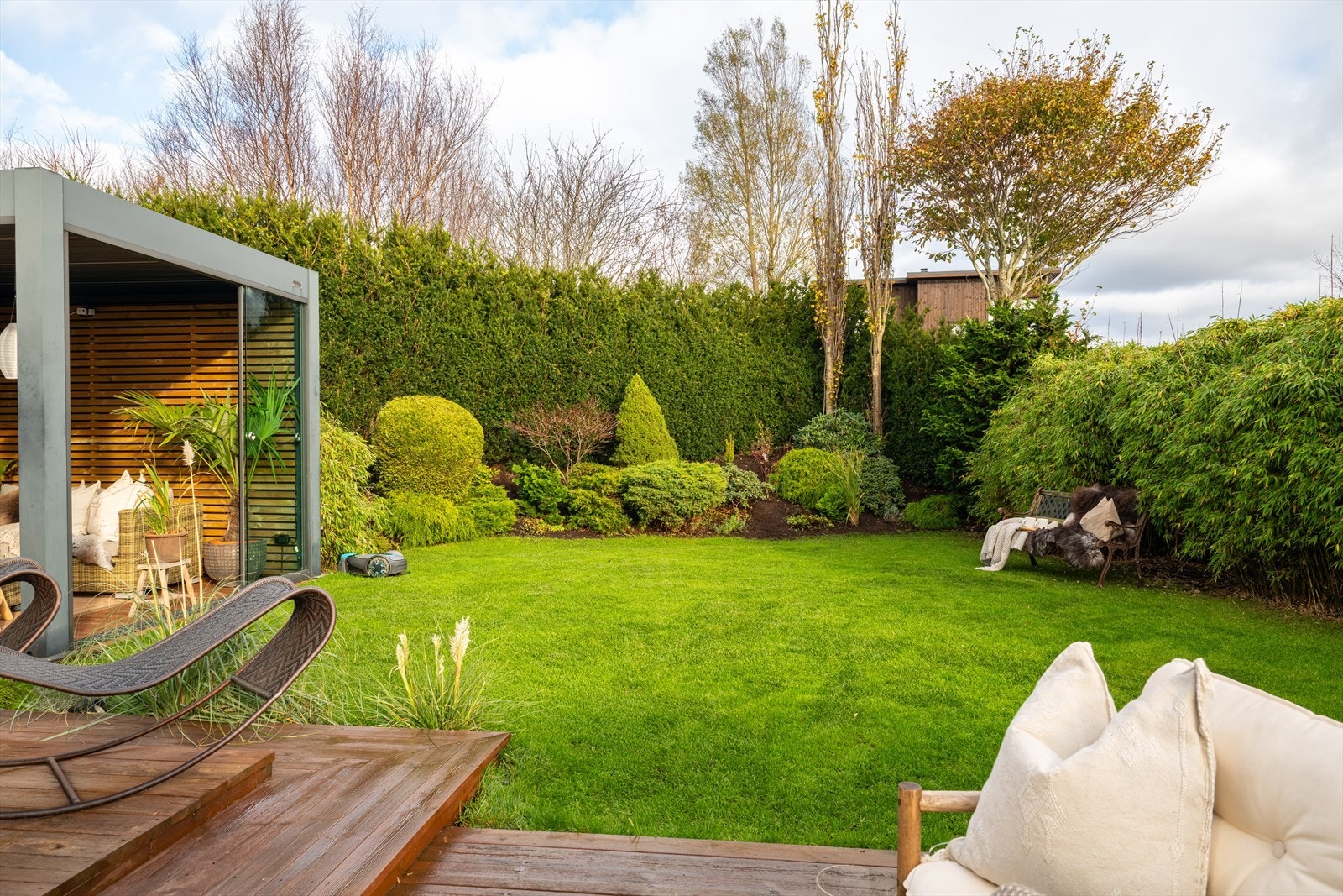 Pent opparbeidet og skjermet hage med frodig beplantning, gressplen og gode uteoppholdssoner, en rolig og privat ramme rundt eiendommen. Galleribilde