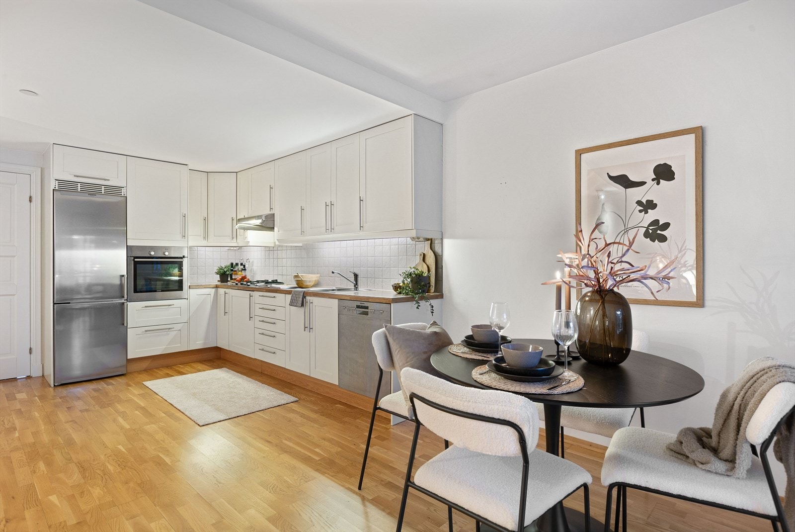 Kjøkkenet har takhøye overskap, og hvite, profilerte fronter. Heltre benkeplate med oppvaskkum med liten skyllekum i rustfritt stål. Galleribilde