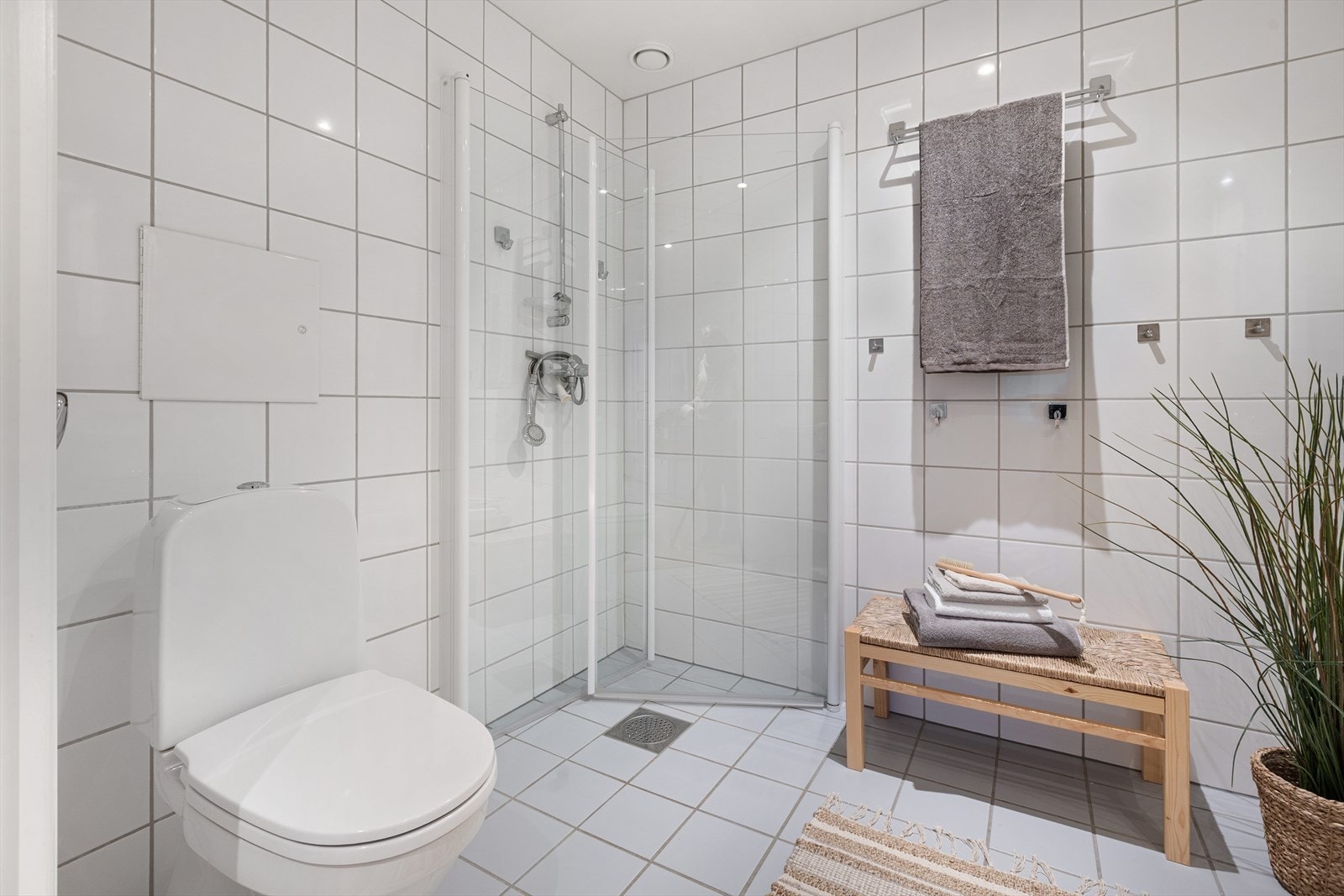 For øvrig er badet utstyrt med gulvmontert toalett og dusjhjørne med innfellbare dusjdører og veggmontert dusjbatteri. Galleribilde