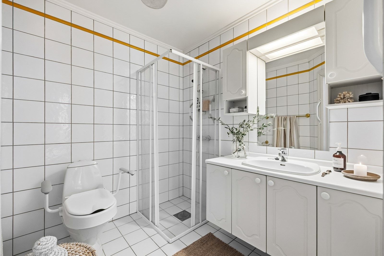 Komplett baderom med flislagte gulv og vegger, og rikelig skapplass under servanten Galleribilde