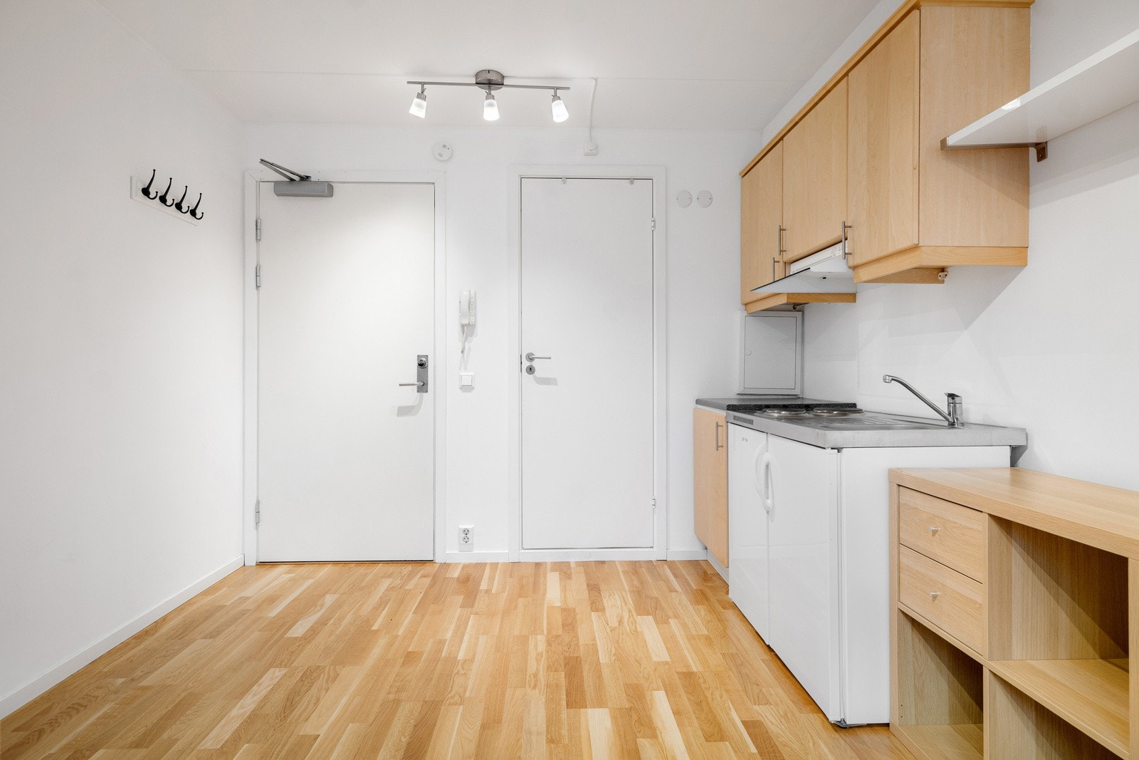 Du ønskes velkommen inn i et oppholdsrom med åpen kjøkkenløsning. Rommet har parkett på gulv, glatte lysmalte overflater og skjult elektrisk anlegg. Galleribilde