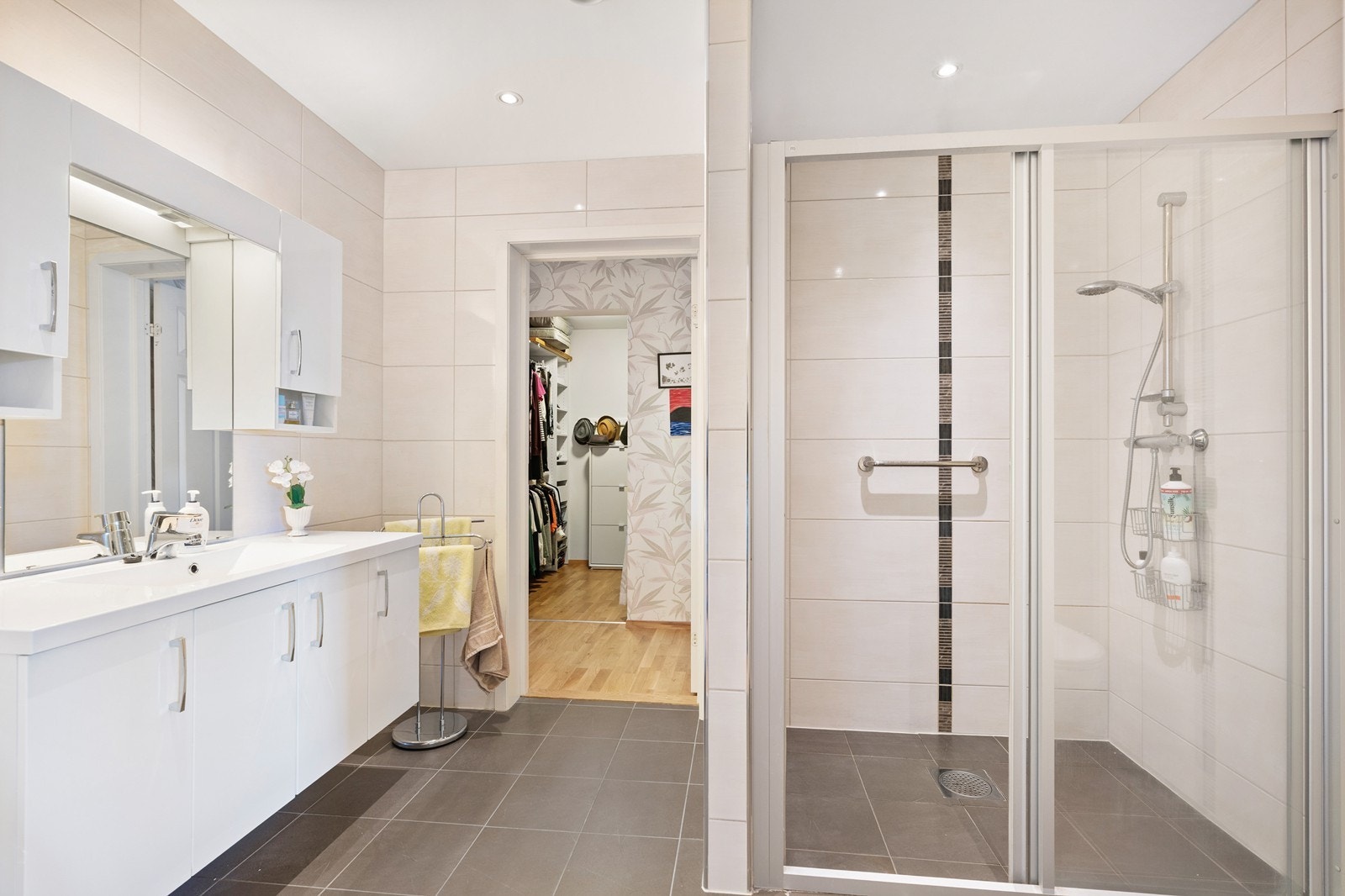 Helfliset delikat bad baderomsinnredning med heldekkende vask, vegghengt toalett og dusjsone med glassdører. Galleribilde