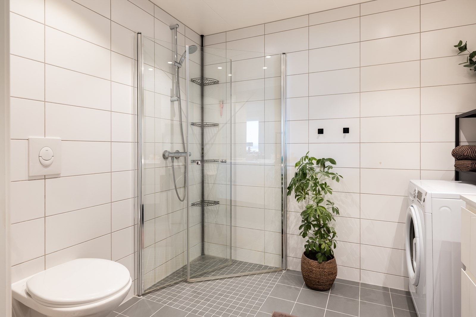 Moderne og flislagt baderom på 5m². Her får du en rekke gode kvaliteter som blant annet innfellbare dusjdører, vegghengt toalett, opplegg for vaskemaskin og varme i gulv. Galleribilde