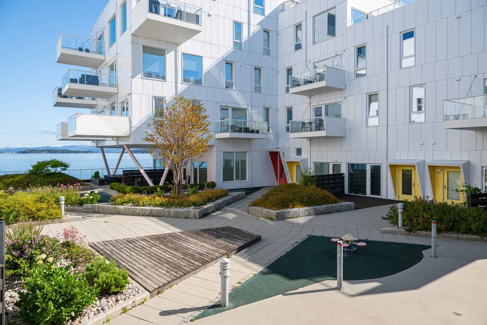 Fellesarealet er pent opparbeidet med belegningsstein, busker og trær, samt lekeplass Galleribilde