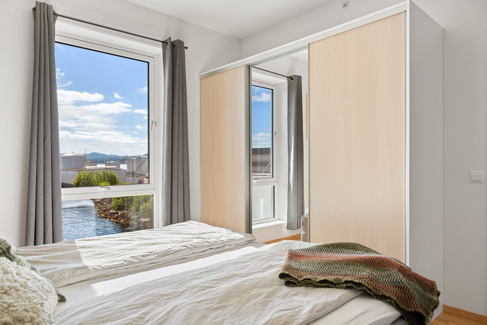 Soverom med garderobeskap og store vindusflater som gir flott utsikt mot sjøen Galleribilde