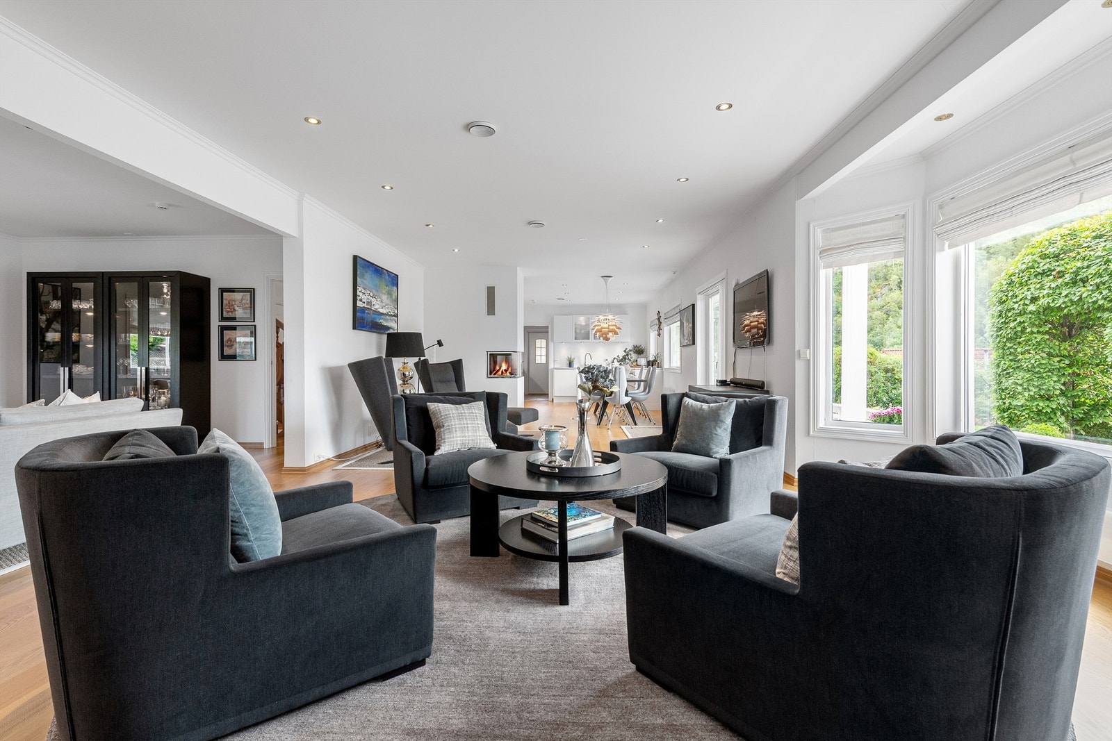 Stuen har direkte utgang til hagen og hagestuen Det er åpent mellom stue og kjøkken og avdelt med en hyggelig peis med glassdører Galleribilde