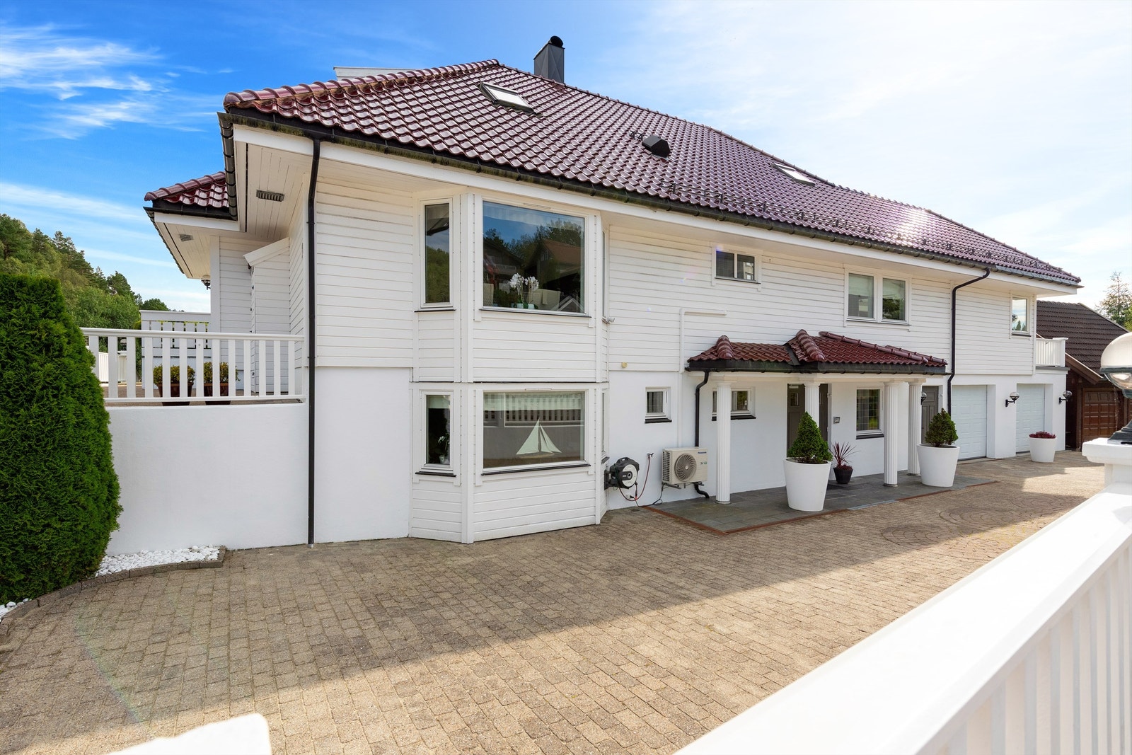 Fasade mot gate med steinlagt gårdsplass som er avskjermet med gjerde mot veien Galleribilde