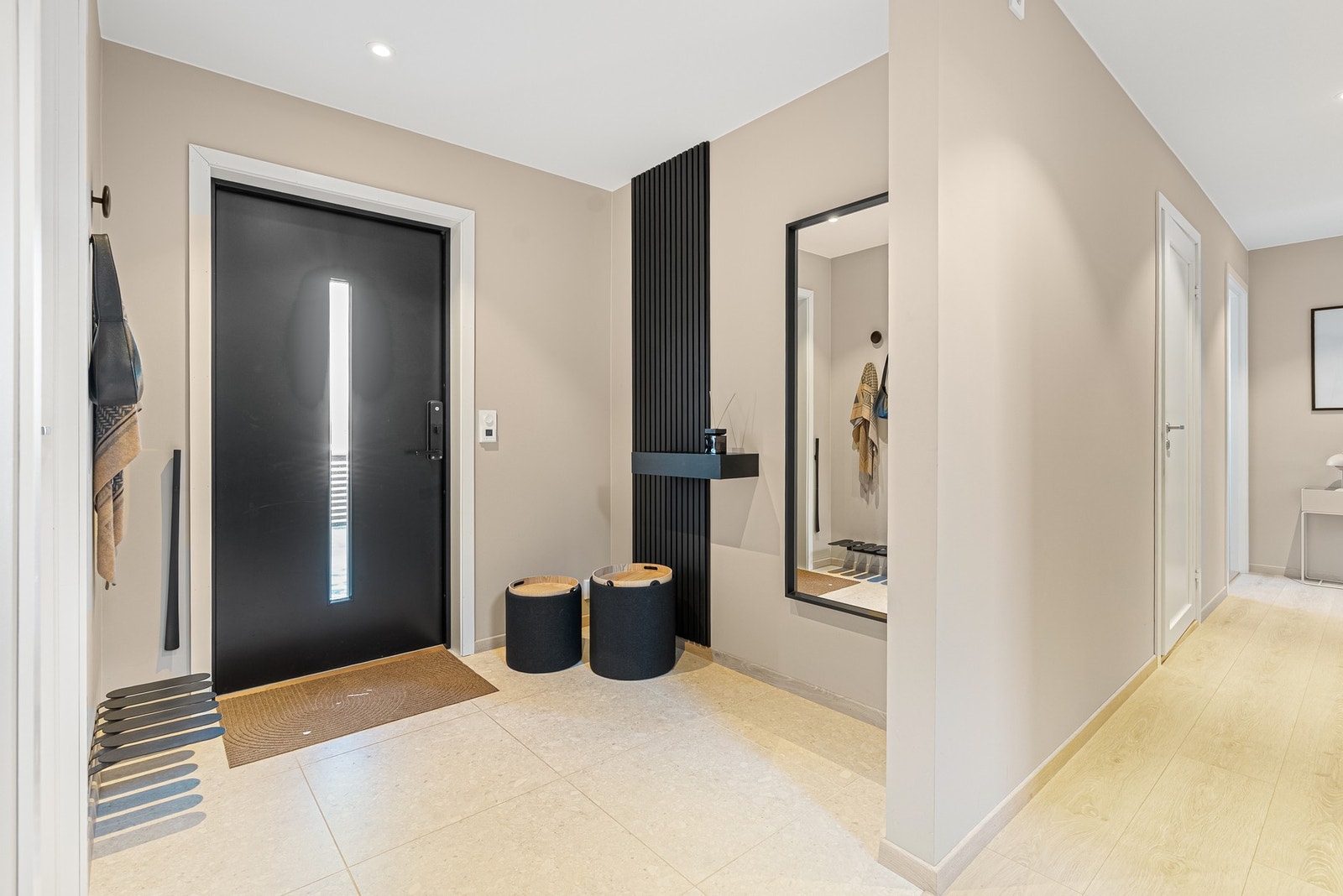 Et lyst og åpent inngangsparti ønsker deg velkommen, med flislagt gulv og moderne detaljer som understreker boligens stil Galleribilde