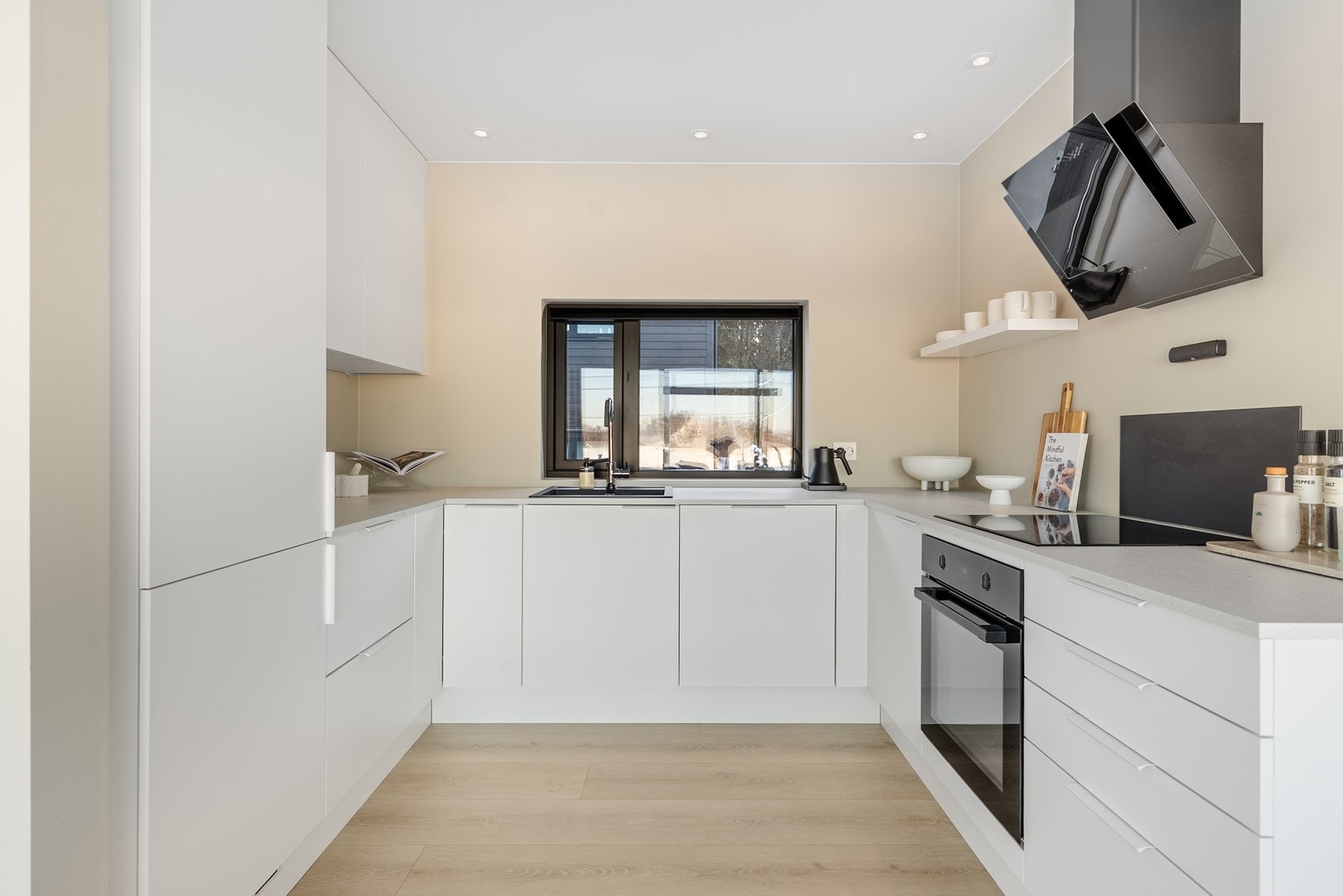 På kjøkkenet har du godt lys via downlights, og god plass for oppbevaring i hvit innredning med slette fronter Galleribilde