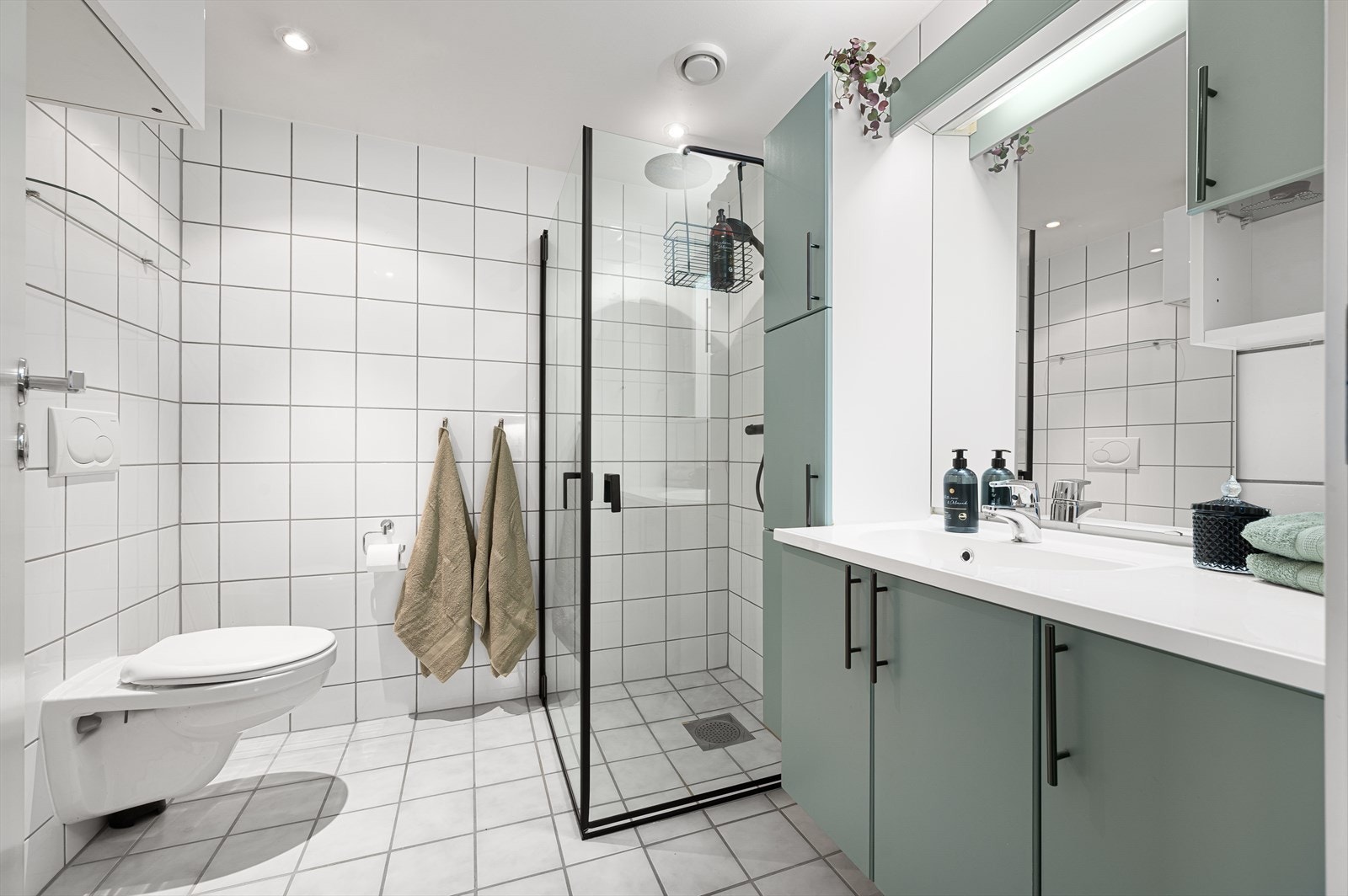 Flislagt bad med varme i gulv utstyrt med servant, dusj med glassvegger, veggmontert W.C. Galleribilde