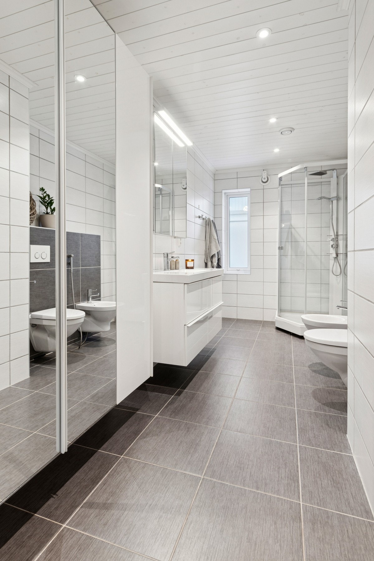 Badet er innredet med nedfelt servant, veggmontert toalett, bide og dusjkabinett. Det er balansert ventilasjon. Galleribilde