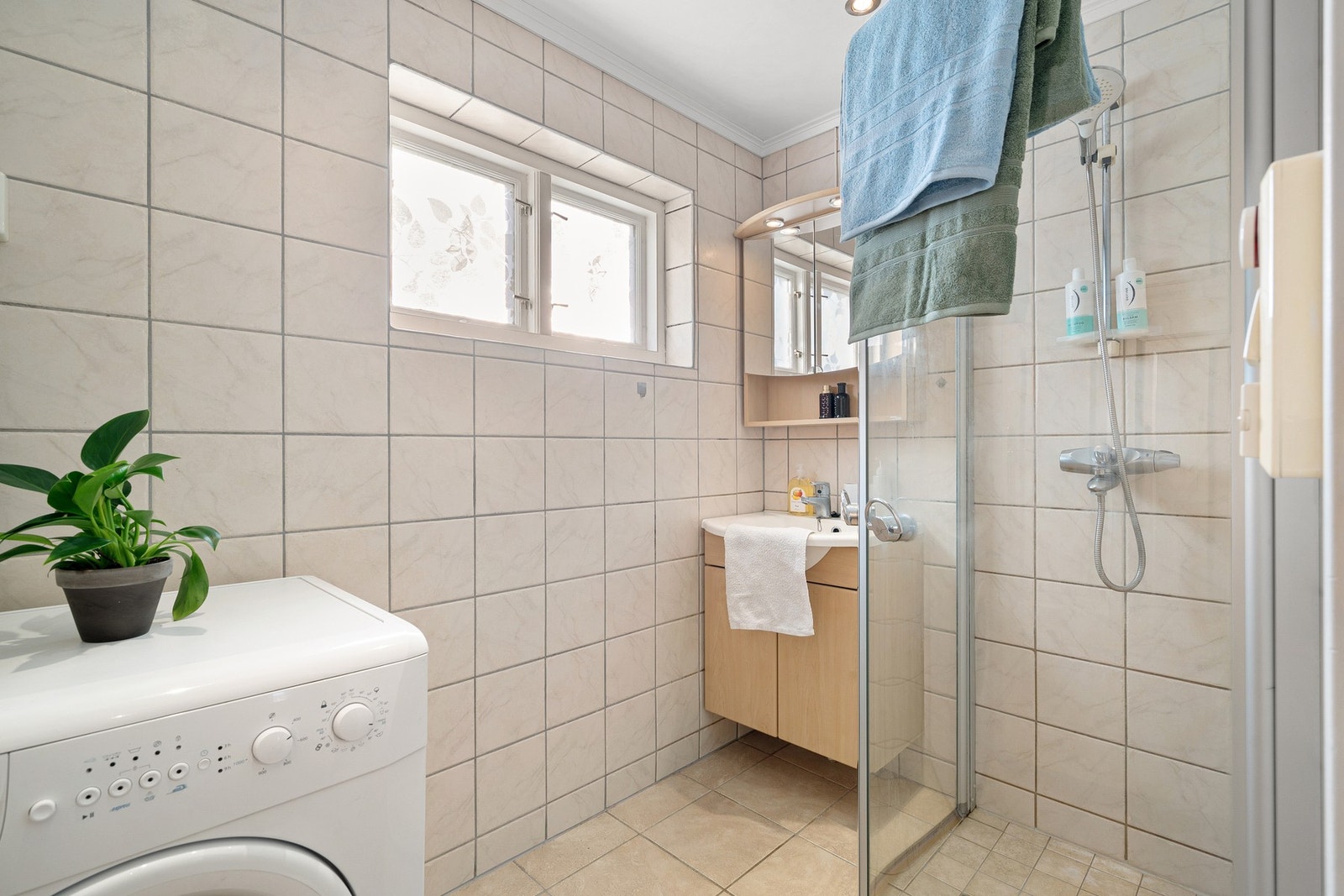 Nøytralt og pent bad med flislagt gulv og vegger. Spotter i tak og dusjhjørne med innfellbare glassdører. Galleribilde