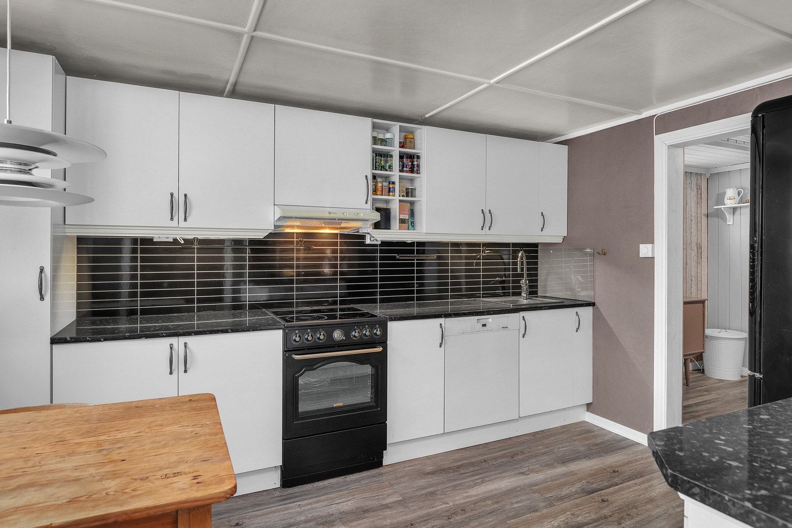 Lyst og praktisk kjøkken med slette fronter og benkeplate og "backsplash" i en mørk kontrastfarge Galleribilde