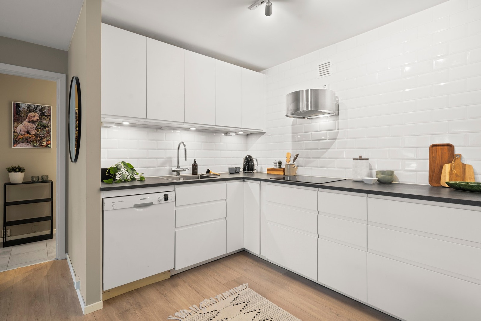 Kjøkkenet er fullt utstyrt med kjøl og fryseskap, oppvaskmaskin, platetopp samt integrert stekeovn og mikrobølgeovn i høyskap, noe som gir god ergonomi og en funksjonell arbeidshøyde. Over benk er det flislagt vegg som understreker det moderne uttrykket, Galleribilde