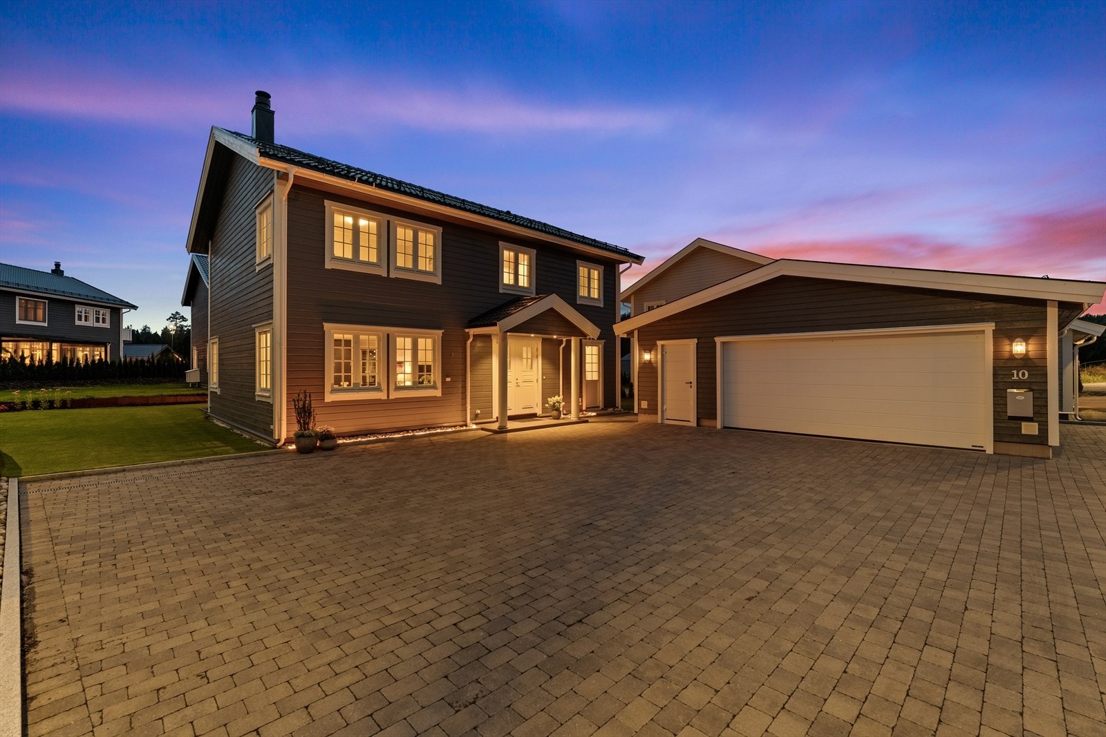 Gårdsplassen er pent opparbeidet med belegningsstein. Parkeringen gjøres i dobbelgarasje med isolert bod, eller på gårdsplassen. Galleribilde