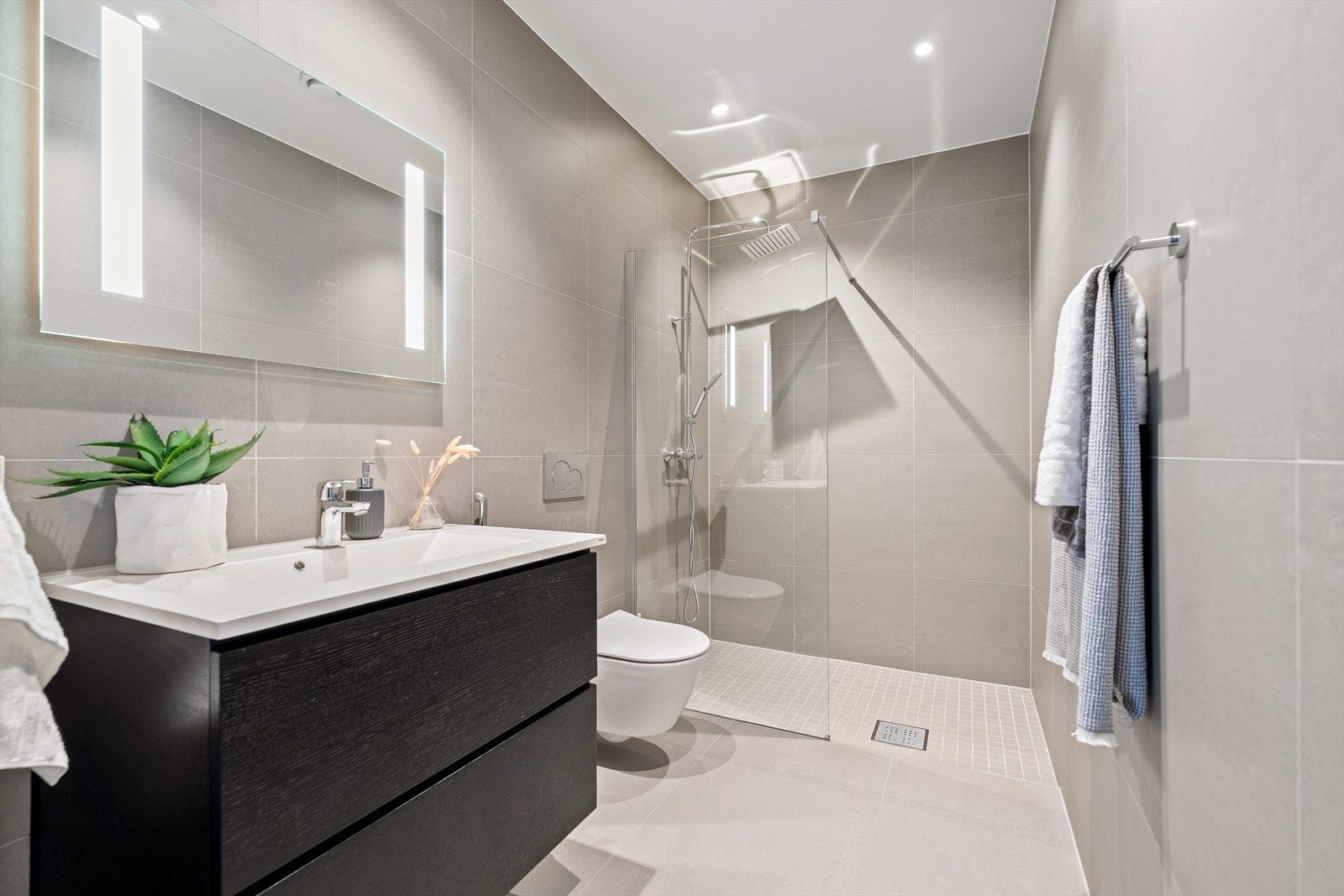 Boligen har to moderne bad, ett i hver etasje. Begge badene er helfliset med beige fliser på gulv og vegger, gulvvarme og downlights. Galleribilde