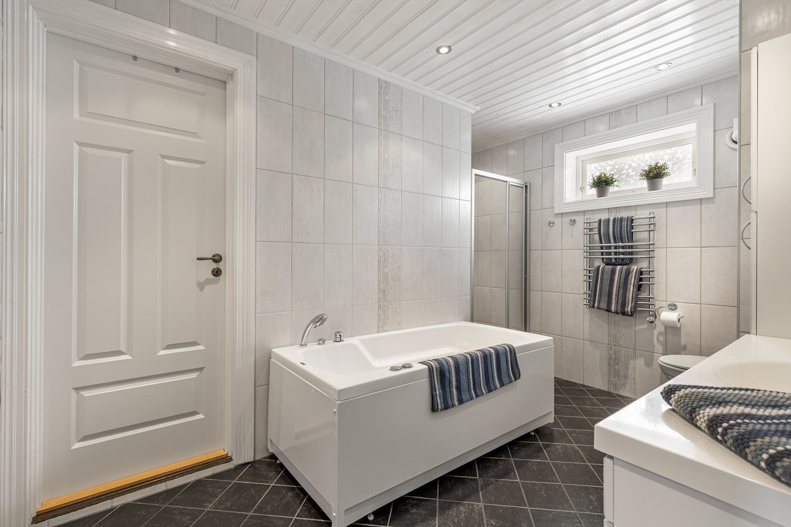 Badet er flislagt med varmekabler og har både badekar samt dusjsone Galleribilde