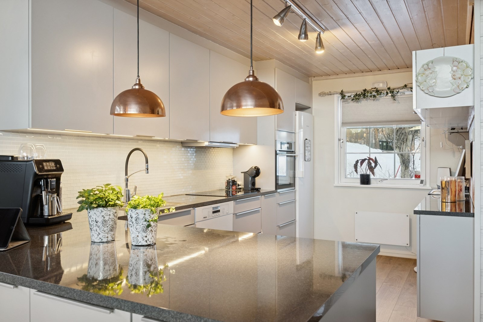 Kjøkkeninnredning med glatte fronter og mørk, slitesterk benkeplate. Galleribilde