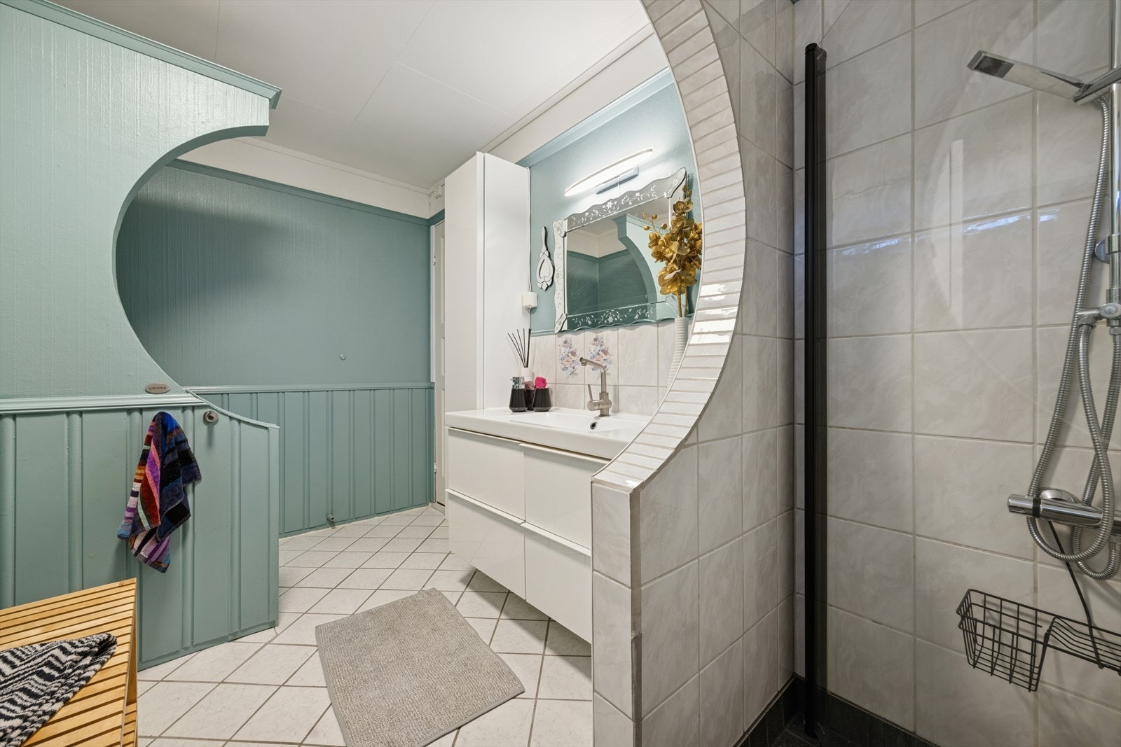 Stort, flislagt bad med servant i seksjon og dusjnisje. Galleribilde