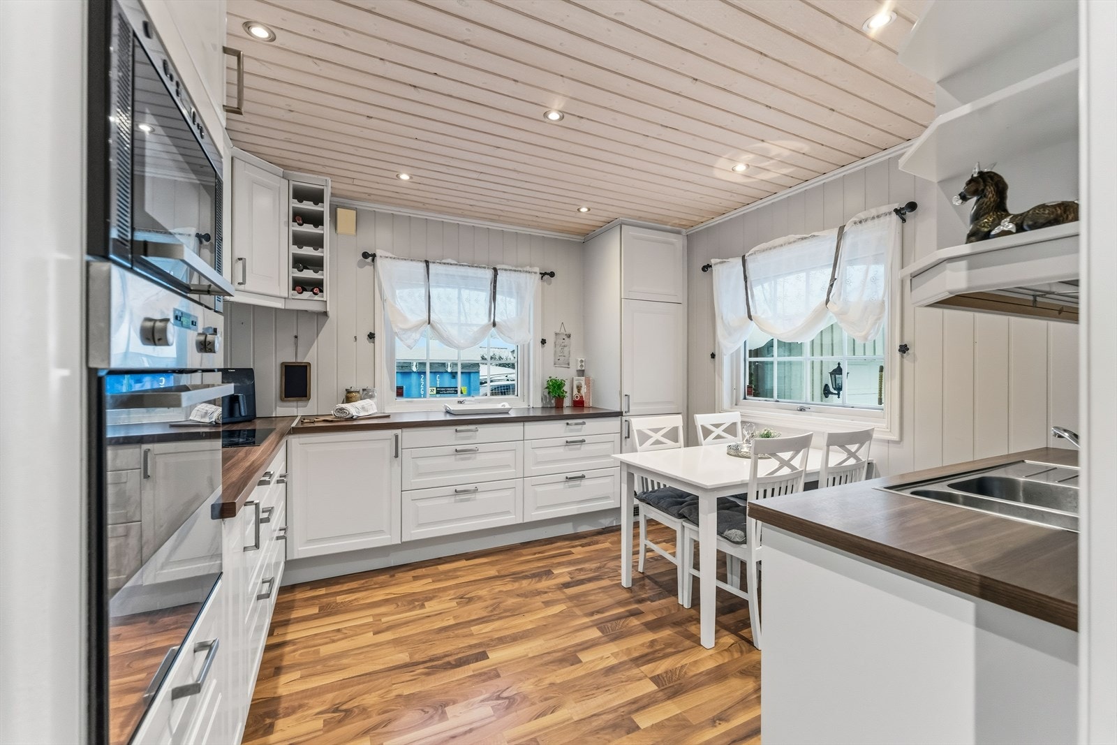 Kjøkkeninnredningen er vinkelformet og har hvite, profilerte fronter og laminert benkeplate. Galleribilde