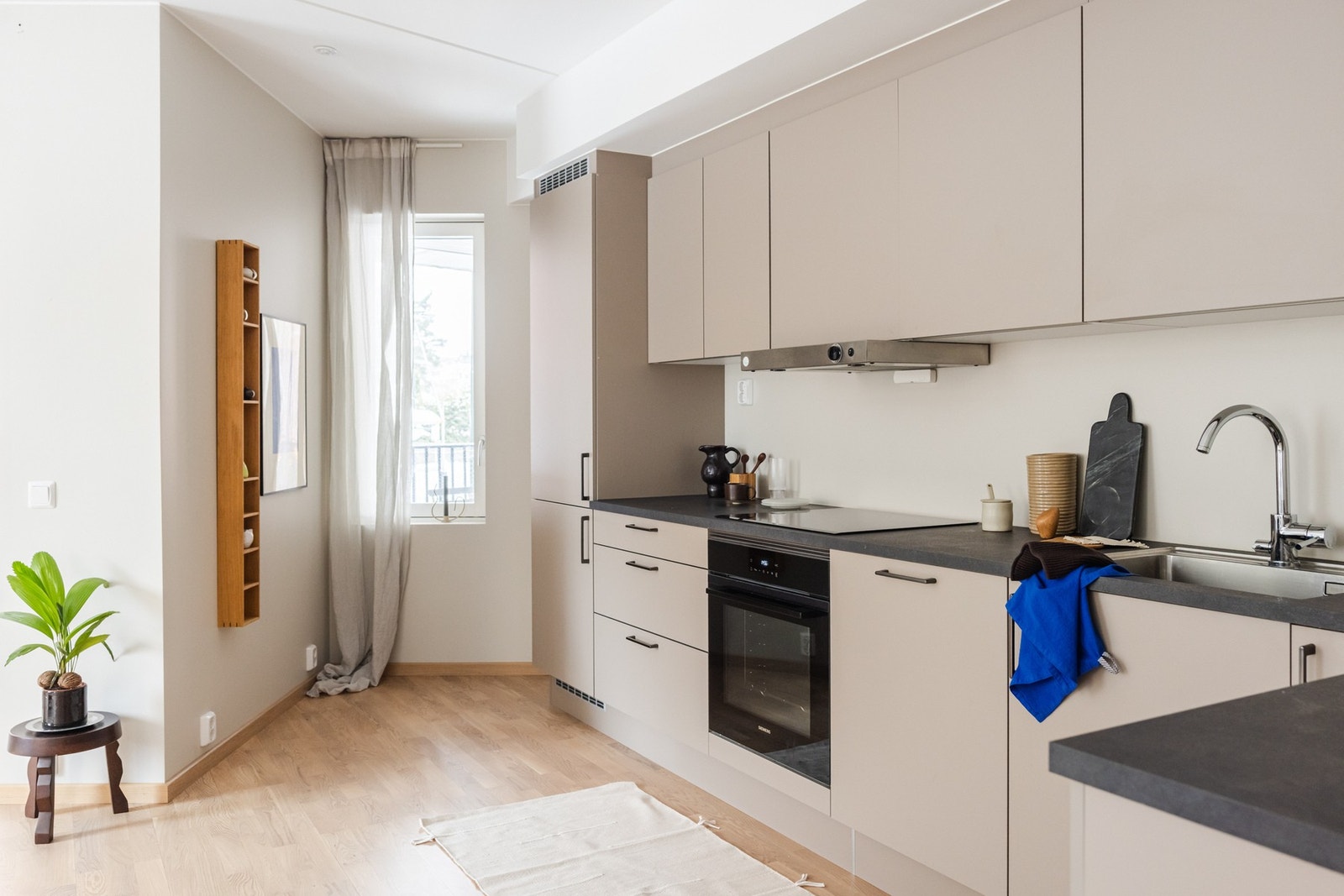 Kjøkkenet i denne leiligheten er gjennomført i en tidløs "Greige" fargetone, som sammen med en mørk grå laminatbenkeplate med "Steinlook" gir et stilig og moderne uttrykk. Galleribilde