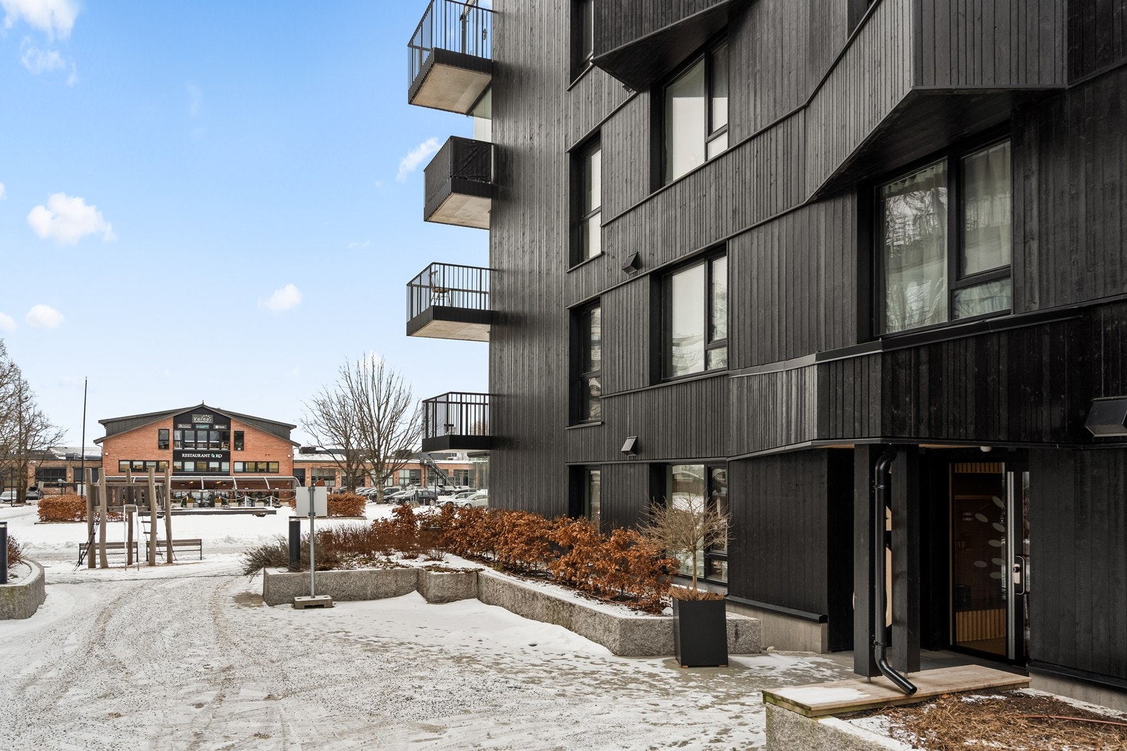 Bygget har en moderne arkitektur med mørk trekledning. Galleribilde