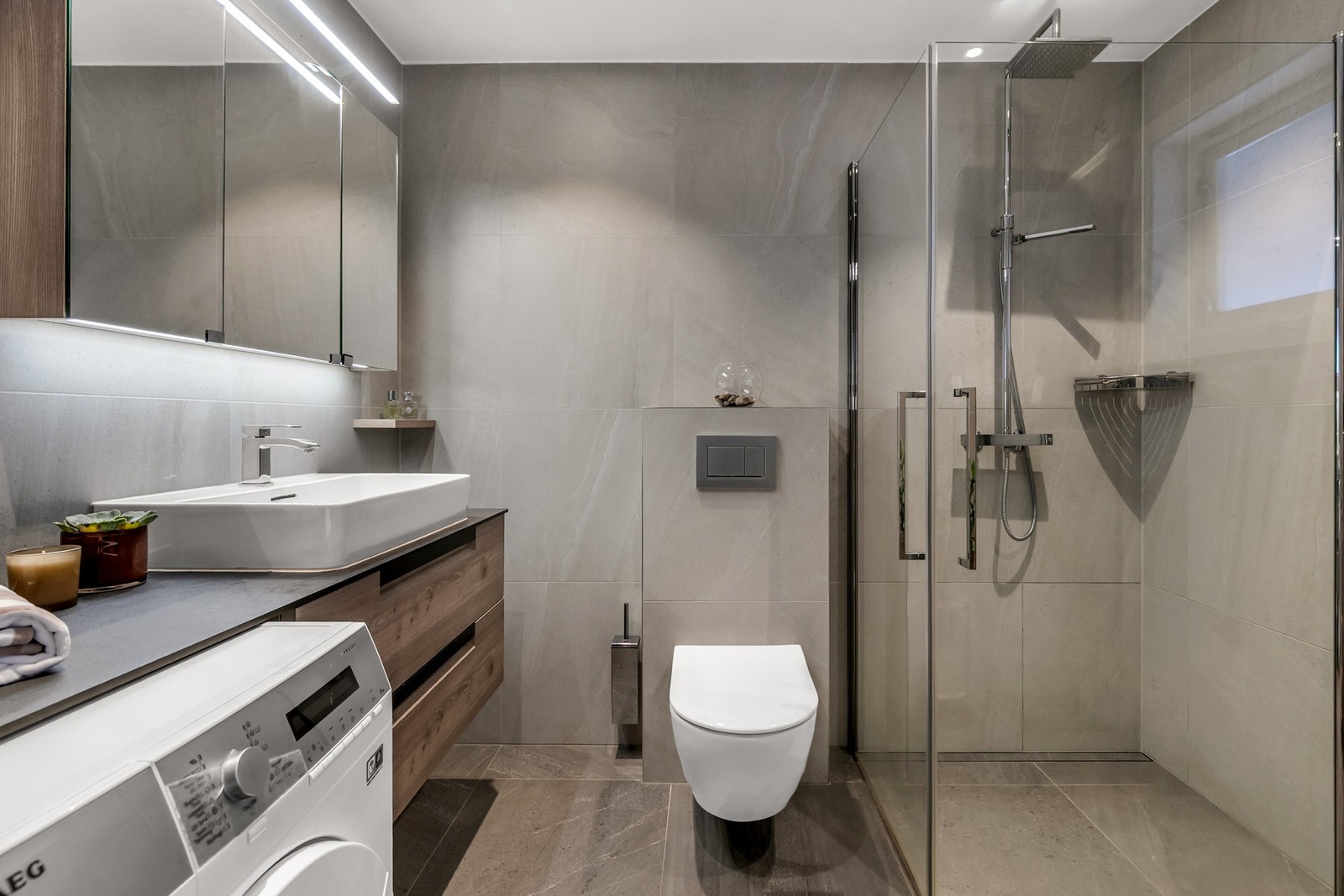 Renovert bad fra 2020. Innredet med vegghengt klosett med innebygd sisterne, dusjsone med innfelte dusjdører i herdet glass og benkeplate i kompositt materiale med topp servant Galleribilde