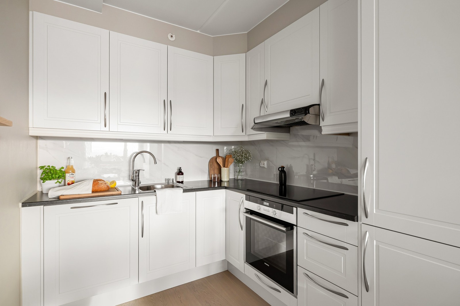 Benkeplate i laminat med nedfelt vask og fliser fra 2025 over benk gir et tidløst og praktisk uttrykk. Galleribilde