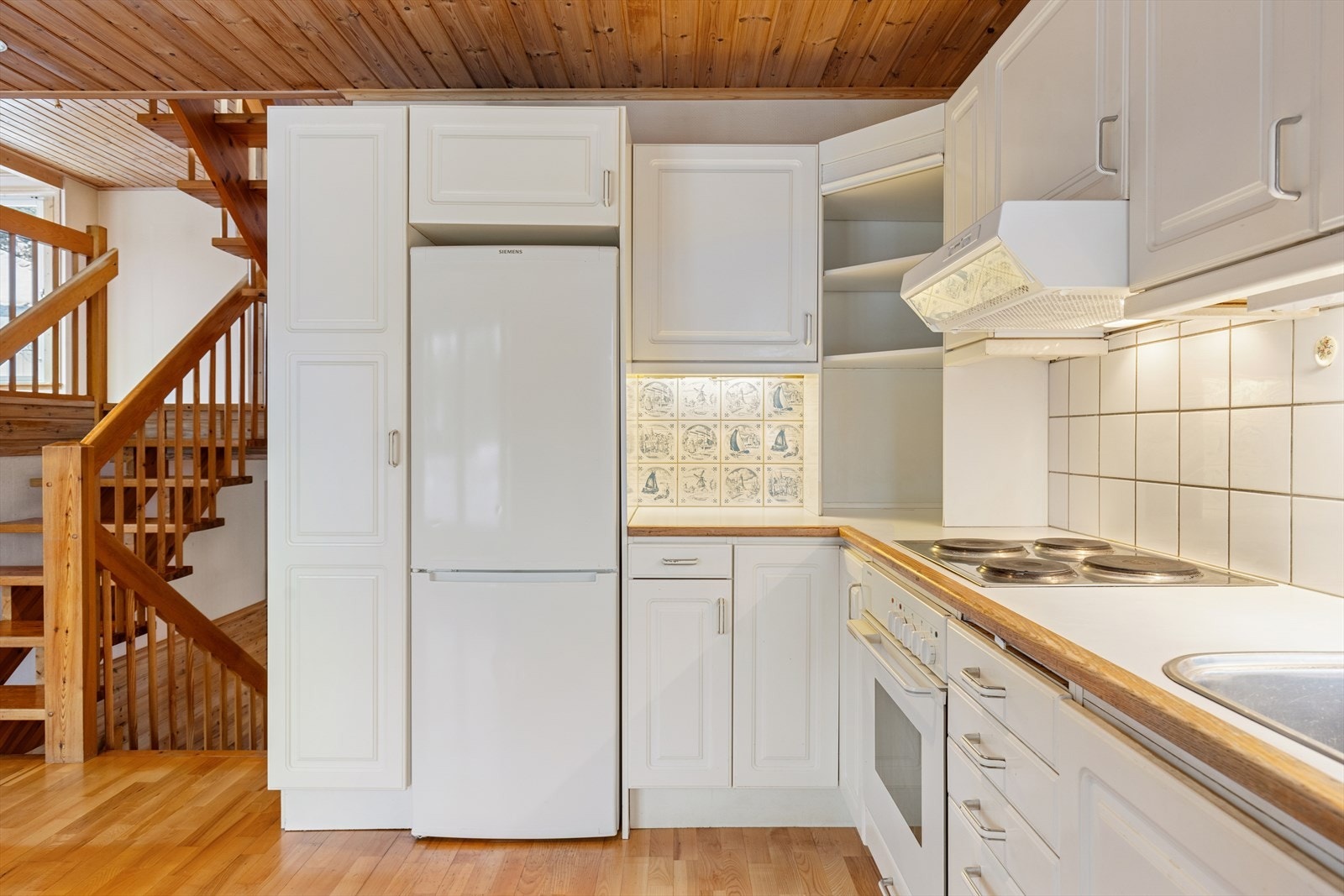 Kjøkkenet fremstår som romslig og funksjonelt, antatt fra byggeåret 1990, med klassisk innredning og profilerte fronter. Rommet har gode arbeidsflater og praktiske løsninger som gjør matlaging og daglige rutiner både effektivt og hyggelig. Galleribilde