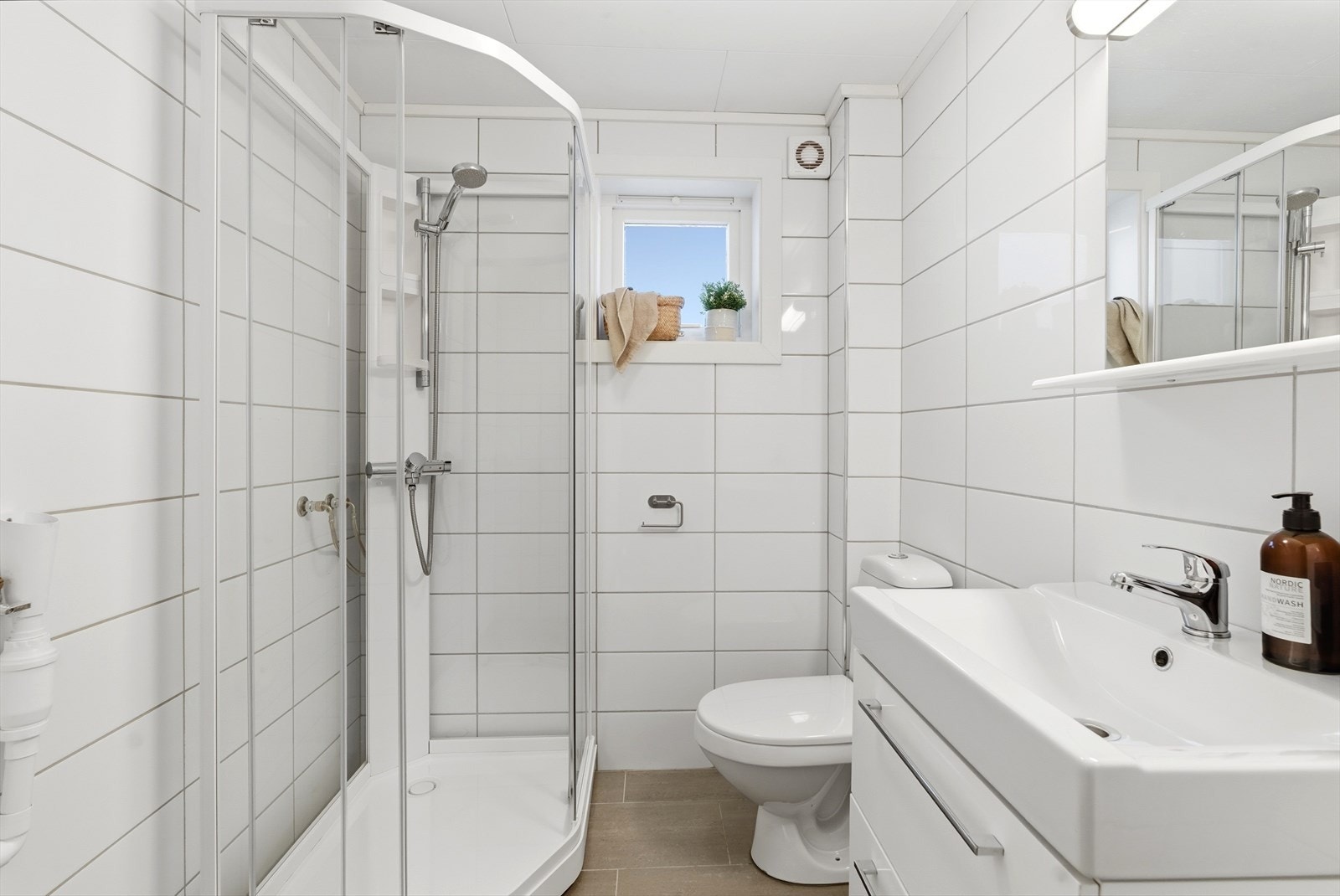 Pent og funksjonelt bad med dusjløsning, servant og toalett Galleribilde