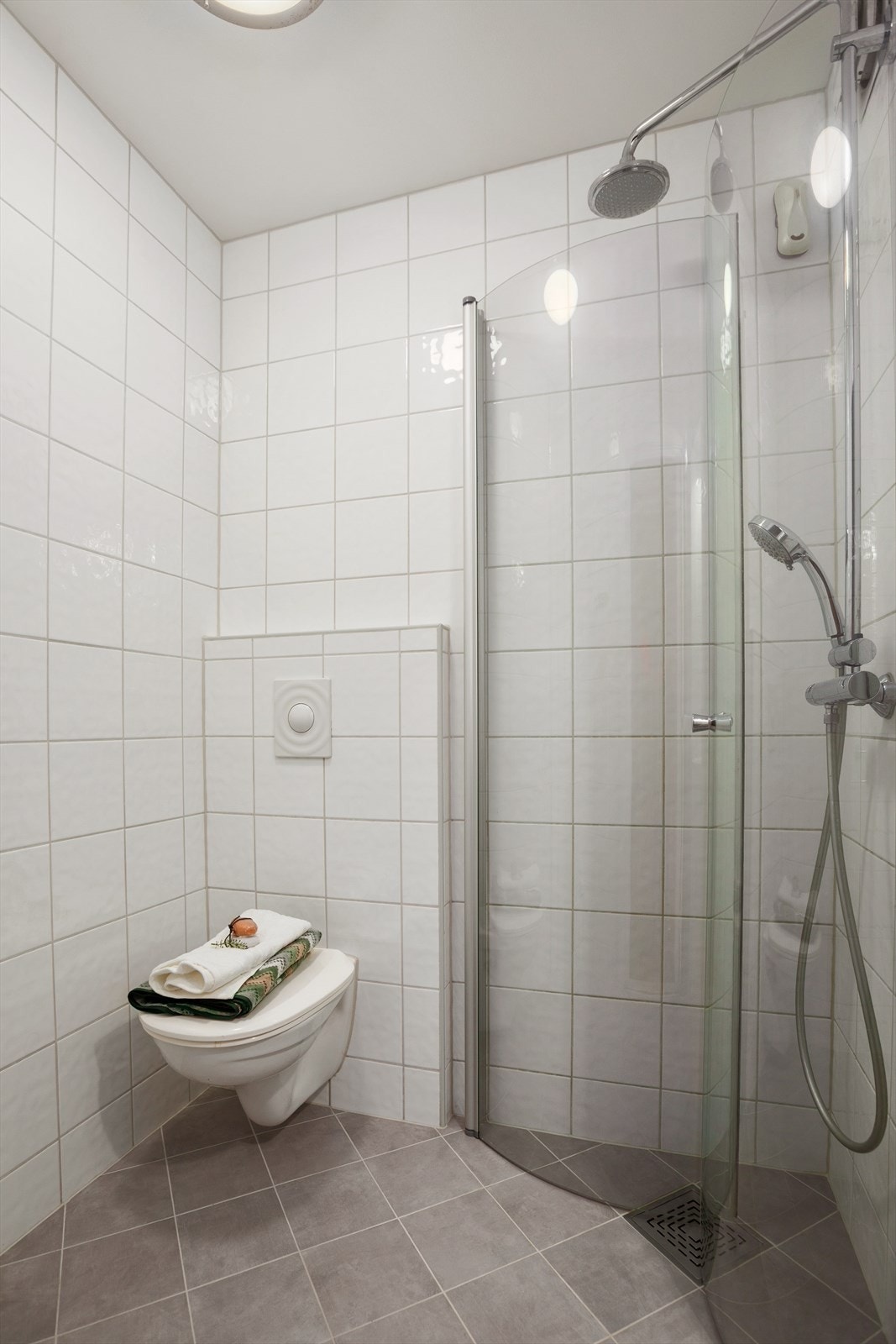 Badet har dusjhjørne med innfellbare glassdører og vegghengt toalett. Galleribilde