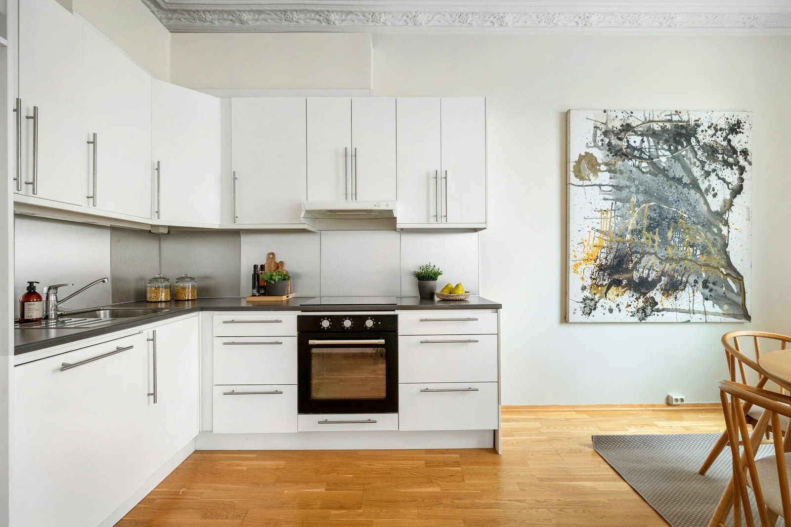 Kjøkkeninnredningen har glatte, hvite fronter og laminat benkeplate Galleribilde