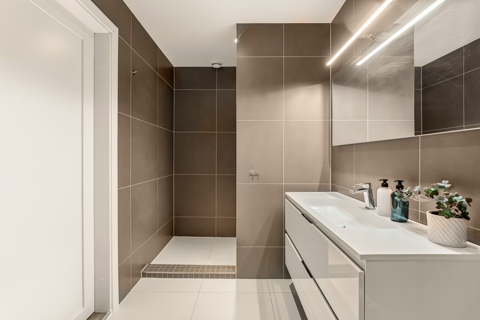 Badet i 1. etasje har et mer markant og moderne uttrykk med mørkere fliser som skaper en lun og elegant atmosfære. Galleribilde