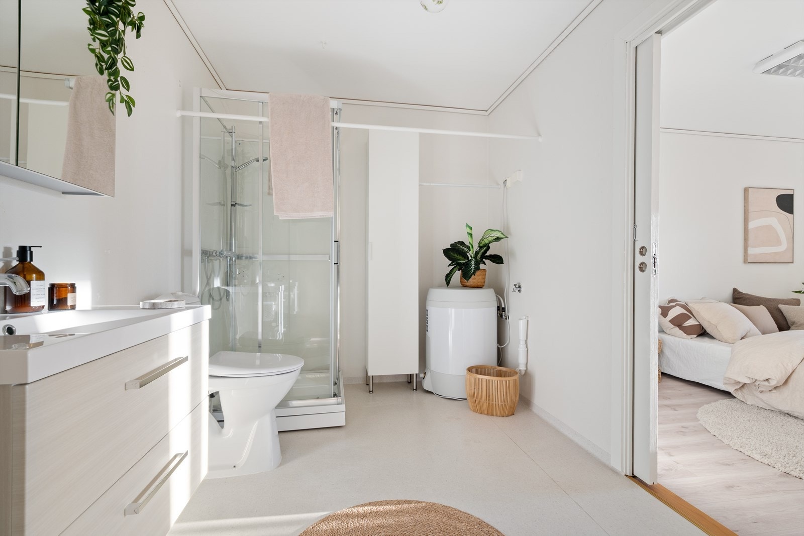 Romslig bad innredet med dusjkabinett, servant i møbel, skap, toalett, varmtvannsbereder og opplegg for vaskemaskin. Galleribilde