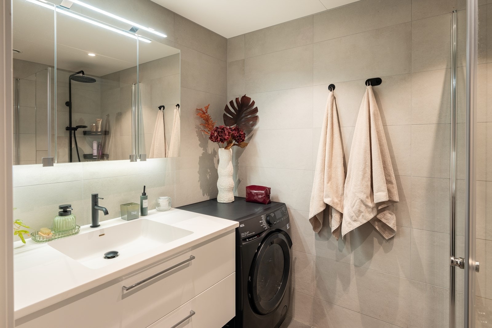 Delikat og flislagt baderom på 4m². Det er rikelig med oppbevaringsplass både i baderomsinnredning og i speilskap. Galleribilde