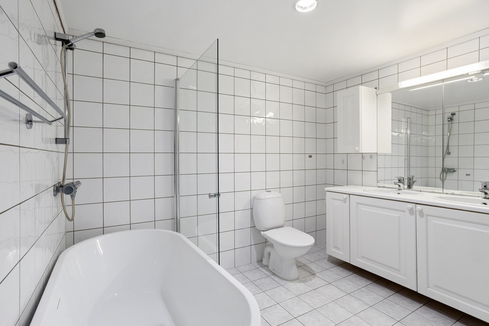 Badet har innredning med 2 nedfelte servanter, toalett, badekar og opplegg for vaskemaskin. Galleribilde