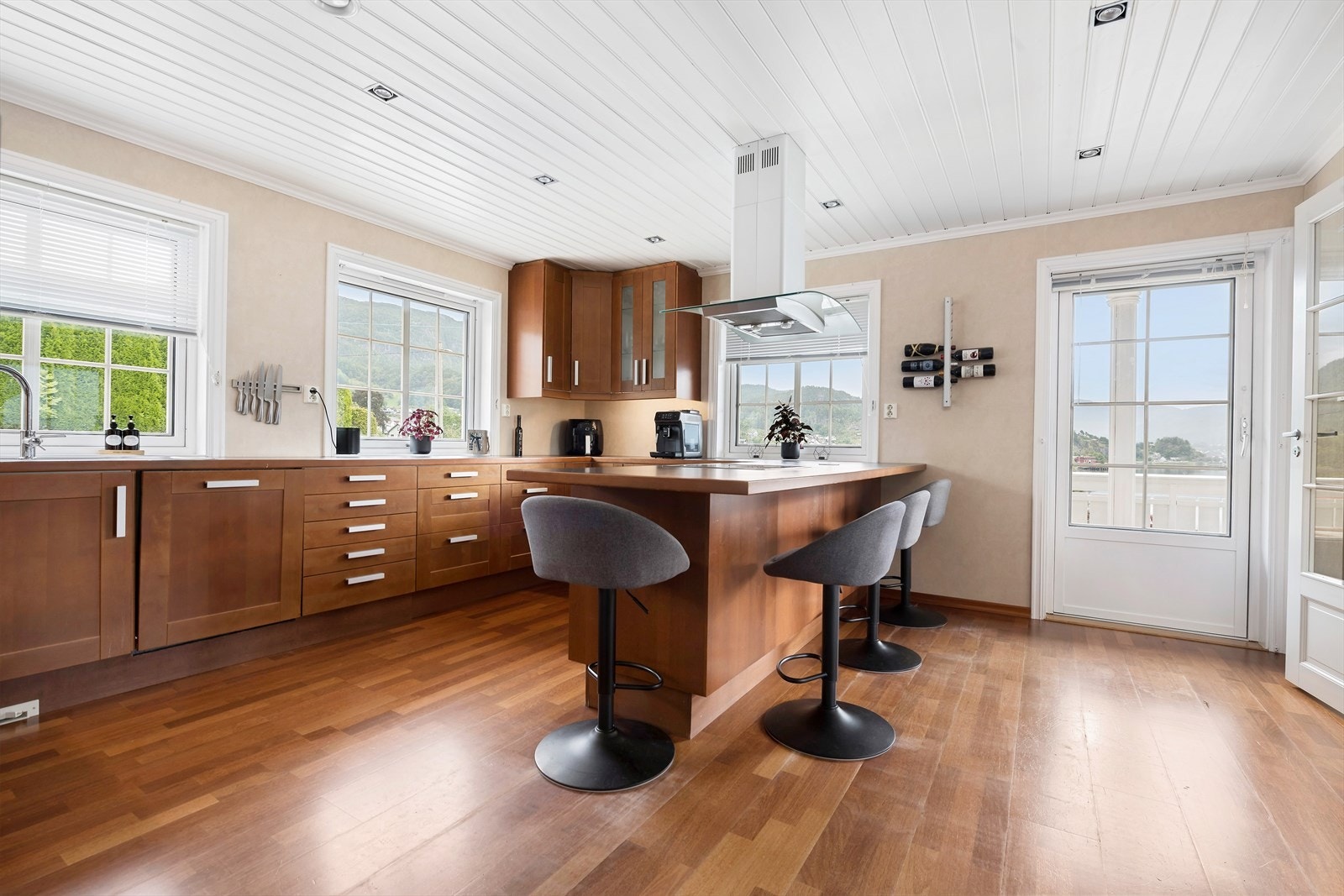 Flott, stort kjøkken med fronter i kirsebær. Kjøkkenøy med spiseplasser og platetopp Galleribilde